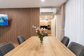 Ein Essbereich mit einem Holztisch, grauen Stühlen und einer Vase mit Blumen.