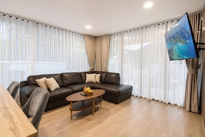 Ein modernes Wohnzimmer mit einem Ecksofa, einem Holztisch und einem flachbildfernseher an der Wand.