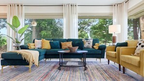 Un salon moderne avec un canapé d’angle, une table basse ronde et un fauteuil jaune.
