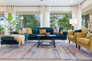 A modern living room with a sectional sofa, a round coffee table, and a yellow armchair. - The Back Nine is your Hot Springs golf course getaway! (Hot Springs)