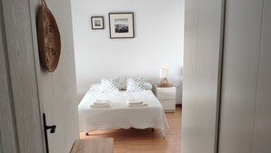A bedroom with a bed, bedside table, lamp, and wall-mounted pictures. - Casa San Miguel: peace and charm in Vejer de la Frontera (Vejer de la Frontera)