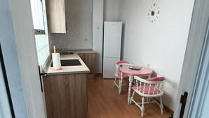 A kitchen with wooden beams, a white refrigerator, a clock, and a dining area with a table and chairs. - Casa San Miguel: peace and charm in Vejer de la Frontera (Vejer de la Frontera)