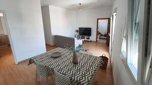 A dining area with a patterned table and chairs, a television in the background, and a staircase leading to another level. - Casa San Miguel: peace and charm in Vejer de la Frontera (Vejer de la Frontera)