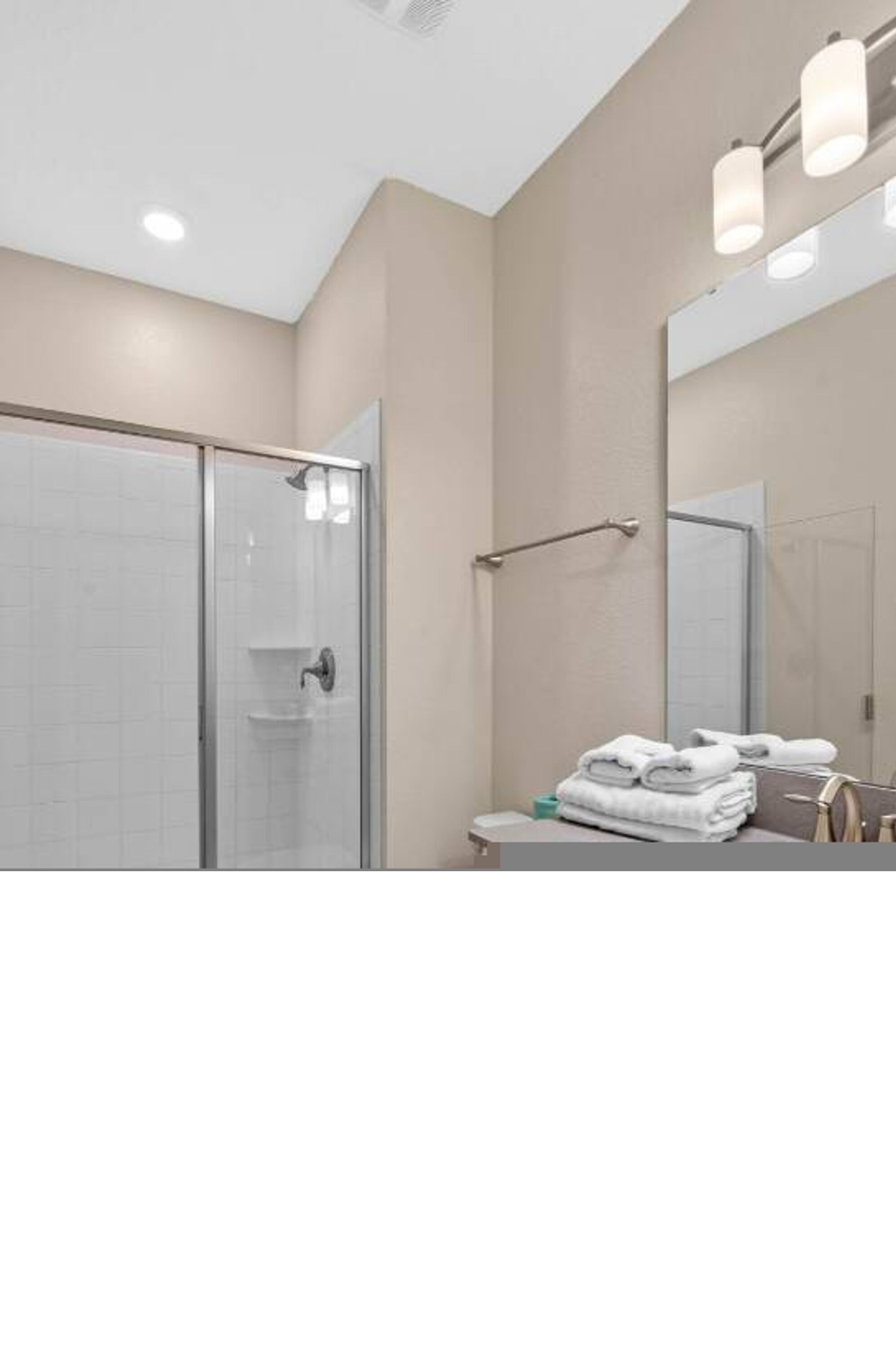 Une salle de bain moderne avec une douche à parois de verre, un lavabo avec un miroir et des serviettes soigneusement pliées.