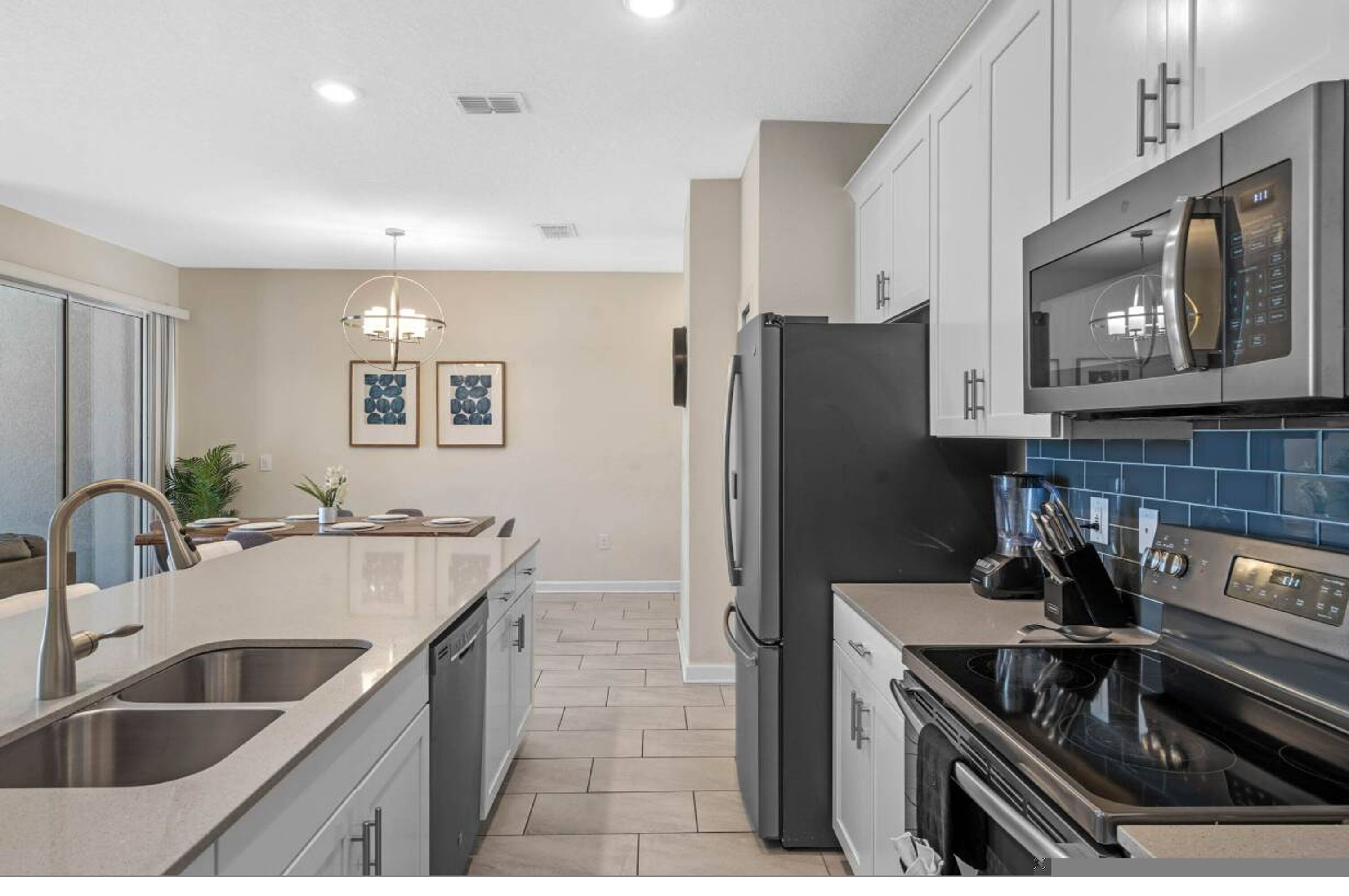 A modern kitchen with a central island, stainless steel appliances, and a blue backsplash.