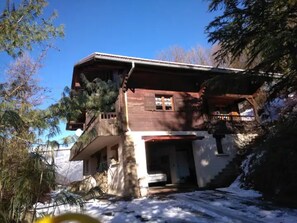 A two-story chalet with a balcony, a stone facade, and a wooden deck. - Chalet "Denali" with Jacuzzi, Mountain View, Private Terrace, and Wi-Fi (Les Clefs)