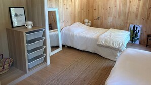 Ein Zimmer mit Holzwandverkleidung, einem Bett, einem Spiegel, einem kleinen Tisch mit einer Lampe und einem Bilderrahmen.