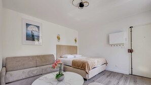 Una habitación moderna con sofá, cama, una mesita de mármol y ventilador de techo.