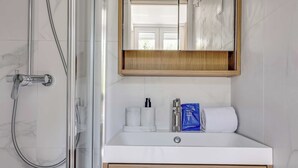 Un baño con ducha, lavabo, espejo y toalla.