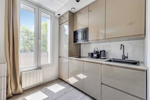 Una cocina moderna con ventana, microondas, hervidor y pileta.