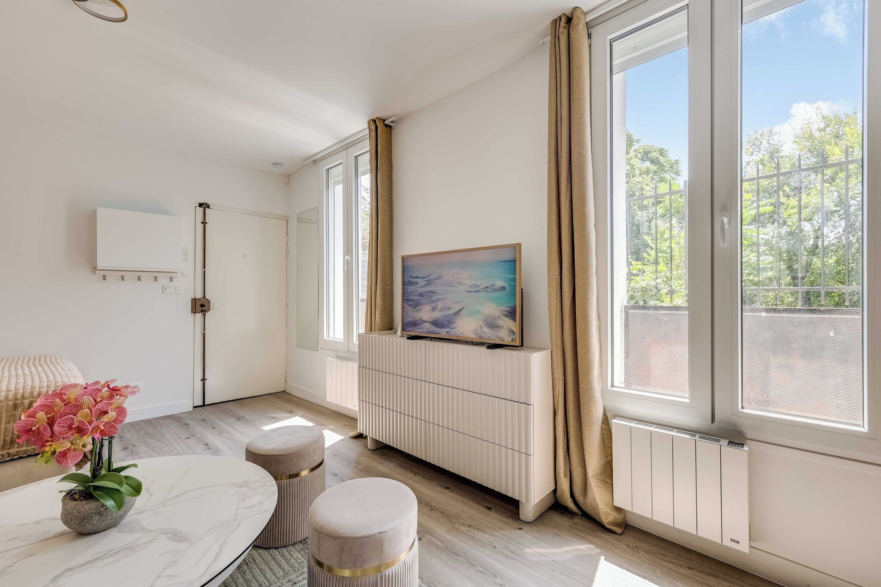 A modern room with a marble table, a potted orchid, a painting, and a radiator.