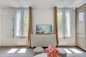 Una habitación con radiador, un cuadro, una ventana con cortinas y una planta.
