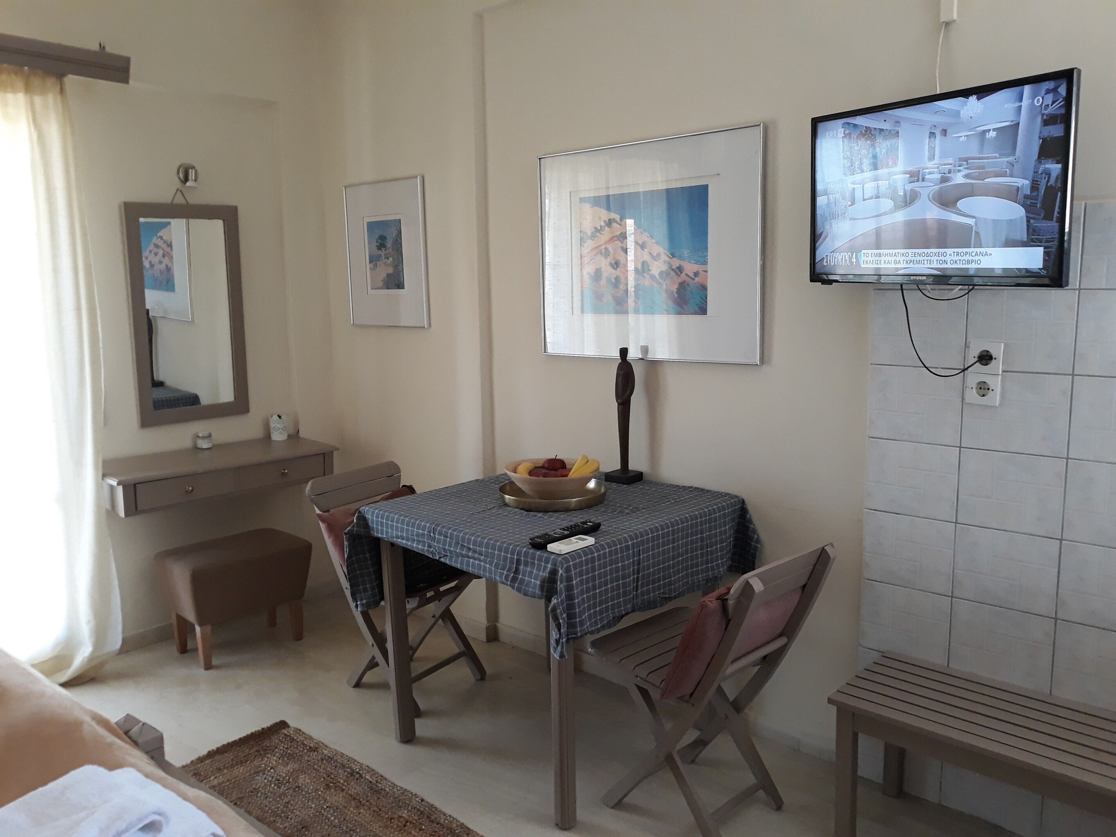 Une chambre d’hôtel équipée d’une table à manger, de chaises, d’un téléviseur et d’œuvres d’art accrochées aux murs.