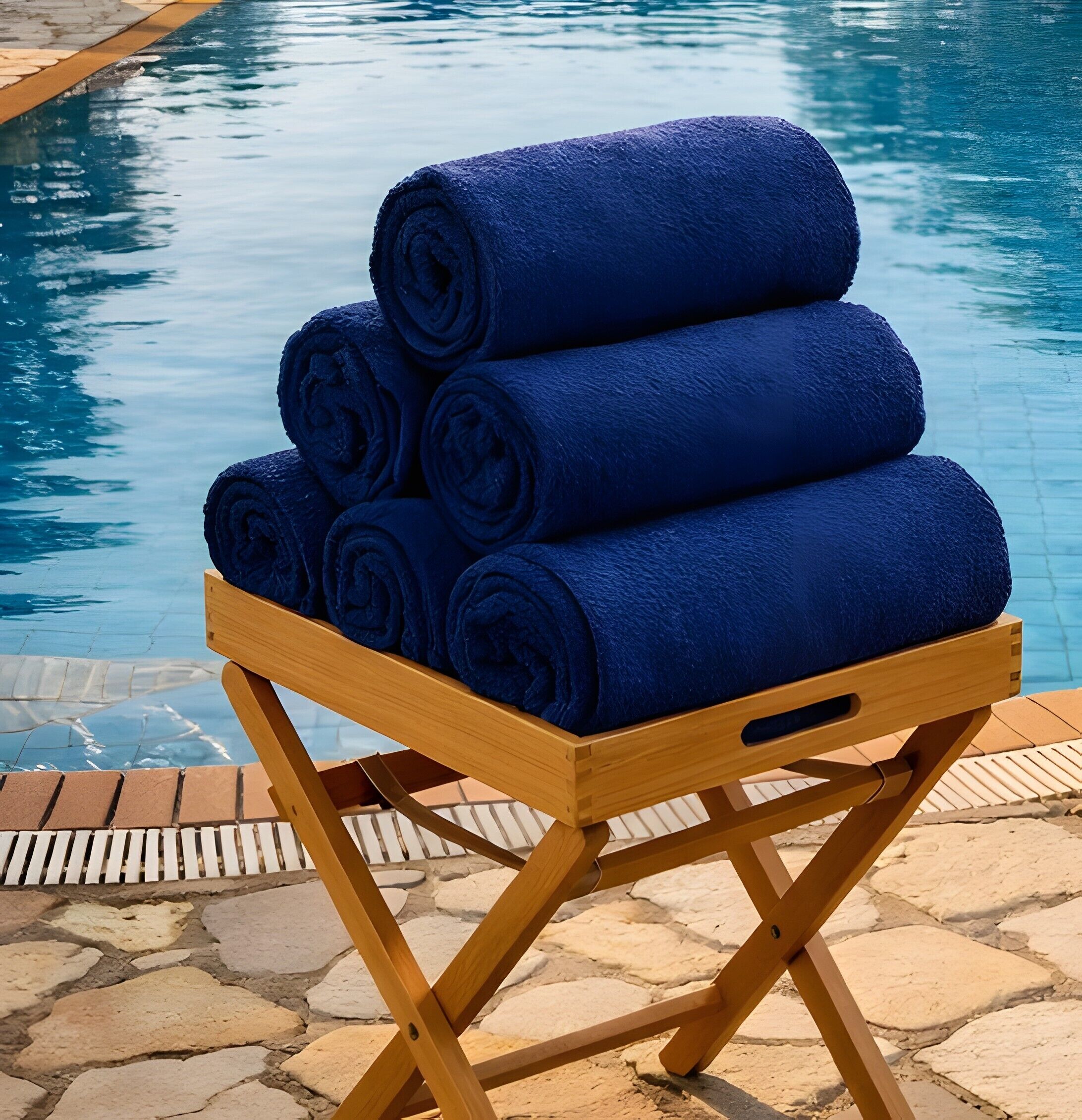 A wooden stand with rolled blue towels by a pool.