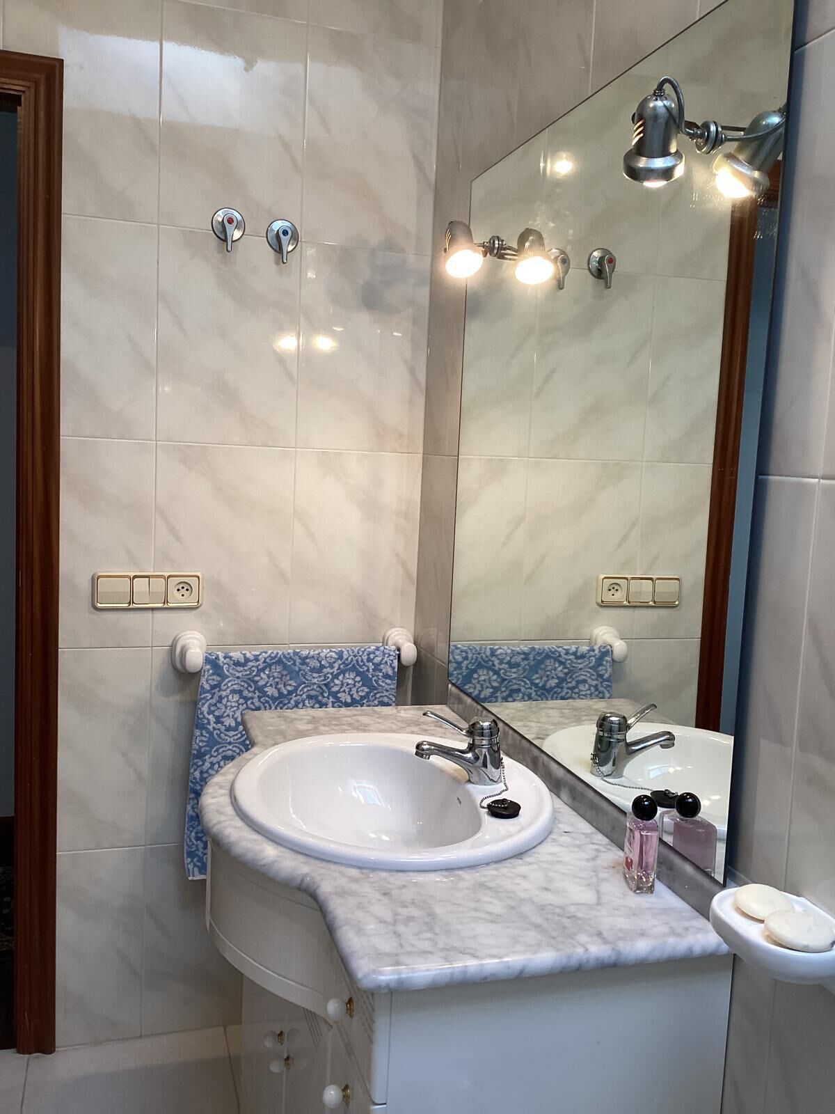 A bathroom with a white sink, a mirror, and a towel rack.