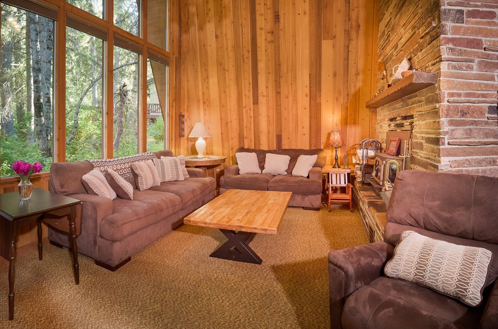 Un salon chaleureux avec des murs en bois, un canapé d’angle, une table basse et une cheminée.