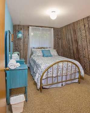 Ein Schlafzimmer mit Bett, Schminktisch, Spiegel und einem Fenster mit Vorhängen.