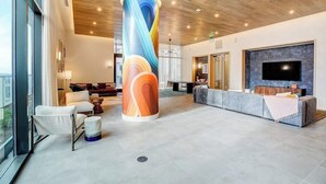 Eine moderne Lobby mit einer großen zylindrischen Säule, Sitzbereich, Rezeption und einem Flachbildfernseher.