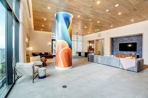 Eine moderne Lobby mit einer großen zylindrischen Säule, Sitzbereich, Rezeption und einem Flachbildfernseher.
