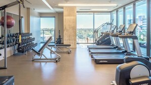 Ein Fitnessstudio mit Laufbändern, Kraftgeräten und einem großen Spiegel.
