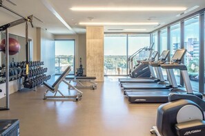A gym with treadmills, weight machines, and a large mirror. - Stylish Rainey Street condo w/private balcony - rooftop pool & gym (Austin)