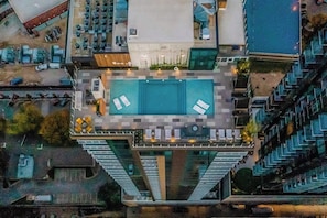 Ein Hochhaus mit Pool auf dem Dach, Sitzgelegenheiten im Freien und Blick auf die Umgebung.