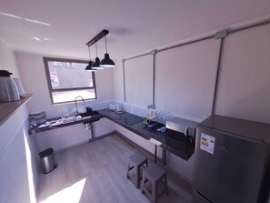 Una cocina compacta con fregadero, encimera y refrigerador.