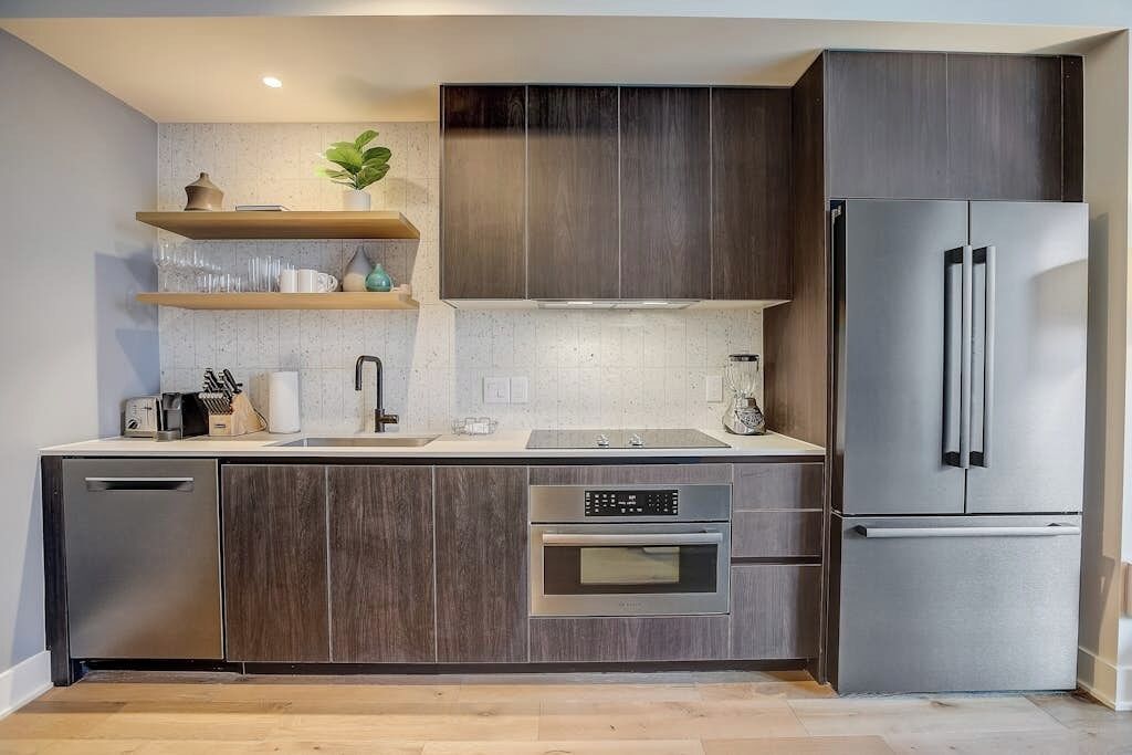 A modern kitchen with dark wood cabinets, stainless steel appliances, and a built-in oven.
