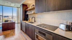 A modern kitchen with dark wood cabinets, a large window, and a city view. - Austin Rainey Street perch with balcony - rooftop pool & gym (Austin)