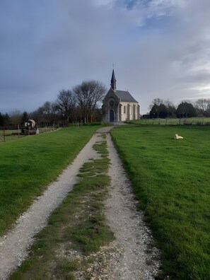 Eine Kirche mit einem Spitzspitzboden, ein Kiesweg, der dorthin führt, und ein eingezäunter Feld.