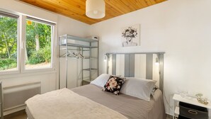 Un dormitorio con cama, armario, radiador y ventana con vista a zonas verdes.