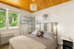 Un dormitorio con cama, armario, radiador y ventana con vista a zonas verdes.