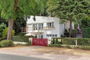 A modern two-story building with a white facade, multiple windows, and a red gate. - Gîte Les Acacias: private terrace, shared garden & Wi-Fi in Saint-Valery-sur-Somme (Saint-Valery-sur-Somme)