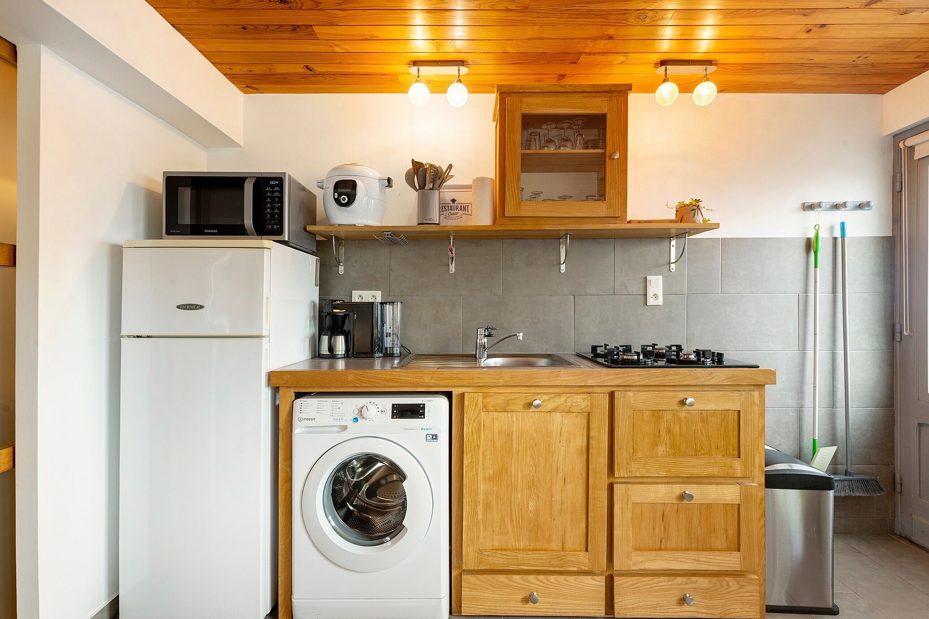 A compact kitchen with a washing machine, microwave, and a stove.