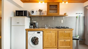 Cocina compacta con lavadora, microondas y estufa.