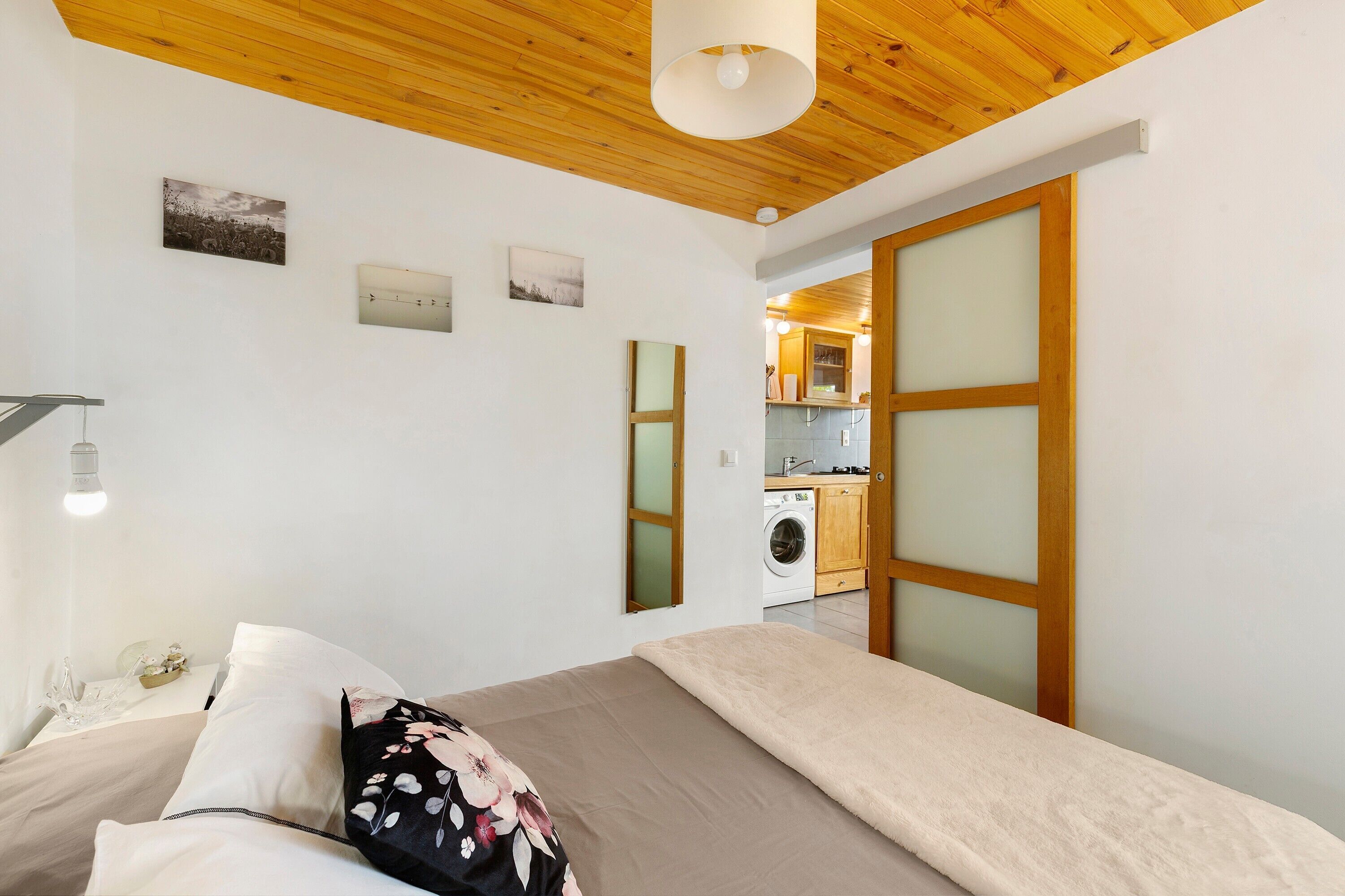 Ein Schlafzimmer mit einem Bett, einem Nachttisch, einer Lampe und einer Wand mit drei gerahmten Bildern.