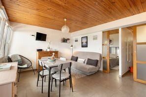 Un espacio de estar moderno con comedor, sofá y televisor montado en la pared.