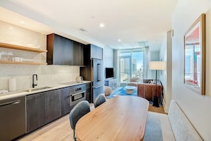 A modern kitchen with a dining area, built-in appliances, and a large window offering a city view. - Natiivo Austin 23rd flr condo - skyline-view balcony - luxe rooftop pool & gym (Austin)