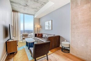 Ein modernes Wohnzimmer mit einer Couch, einem Sessel, einem Couchtisch und einem Fernseher.
