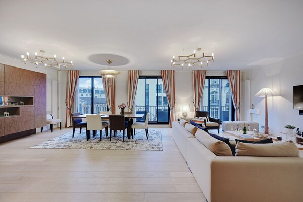 A modern living room with a dining area, large windows, and a sofa. - TOP OF THE RANGE- LUXURY DESIGNER APARTMENT AVE RAYMOND POINACARE (Paris)