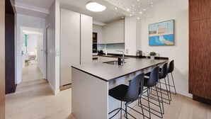 Una cucina moderna con isola centrale, sgabelli da bar e lampada a sospensione.