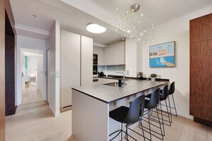 A modern kitchen with a central island, bar stools, and a pendant light. - TOP OF THE RANGE- LUXURY DESIGNER APARTMENT AVE RAYMOND POINACARE (Paris)