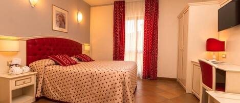 Una habitación de hotel con cama, mesita de noche, lámpara, armario y televisor.