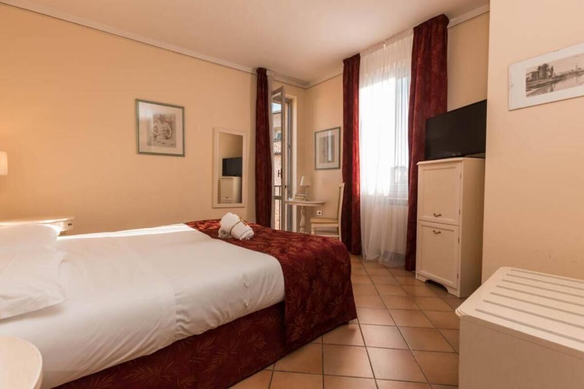 A hotel room with a bed, a desk, a television, and a wardrobe.