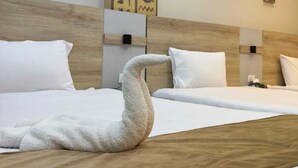 A hotel room with two beds, a wooden headboard, a wall with hieroglyphs, and a swan-shaped towel. - Holiday Escape (Giza)