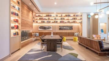 Une bibliothèque moderne dotée d’une grande table en bois au centre, d’étagères et d’espaces aménagés pour s’asseoir.