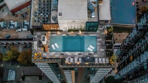 A high-rise building with a rooftop swimming pool, outdoor seating, and a parking area. - Studio condo with rooftop pool, fast WiFi, central AC & private W/D (Austin)