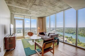 Ein modernes Wohnzimmer mit großem Fenster, einer Couch, einem Couchtisch und einem Sessel.