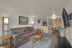 A compact living space with a sofa, coffee table, and a kitchen area with a dining table and chairs.