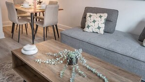 A living room with a wooden coffee table, grey sofa, and matching chairs. - Spacious Renovated 3BR | Free Parking (Montreal)